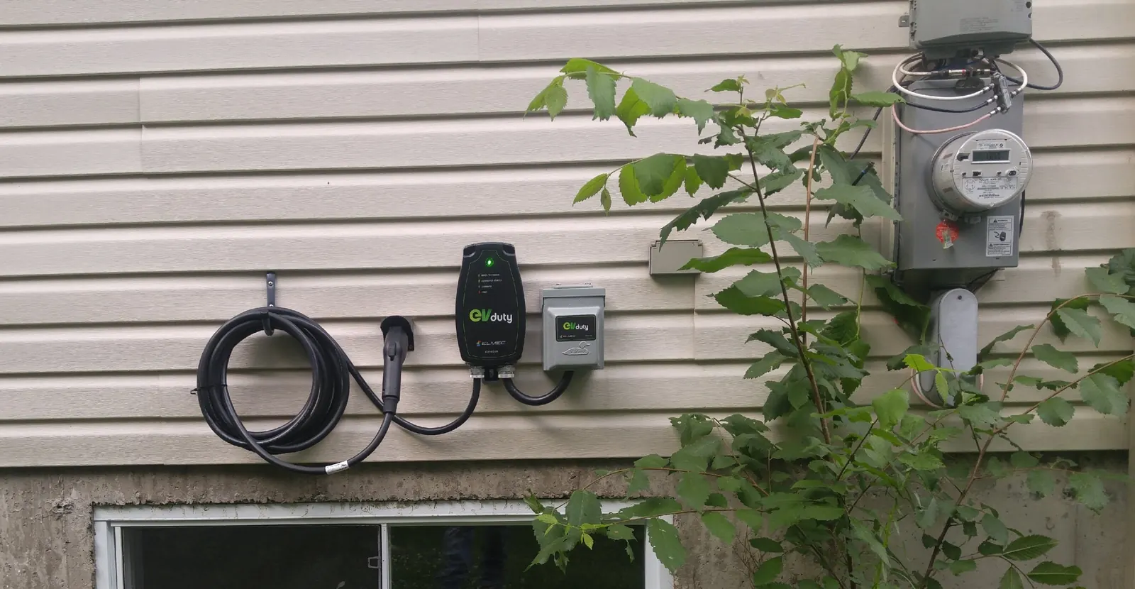 Borne de recharge de niveau 2 installée sur le mur extérieur d'une maison, à côté du compteur