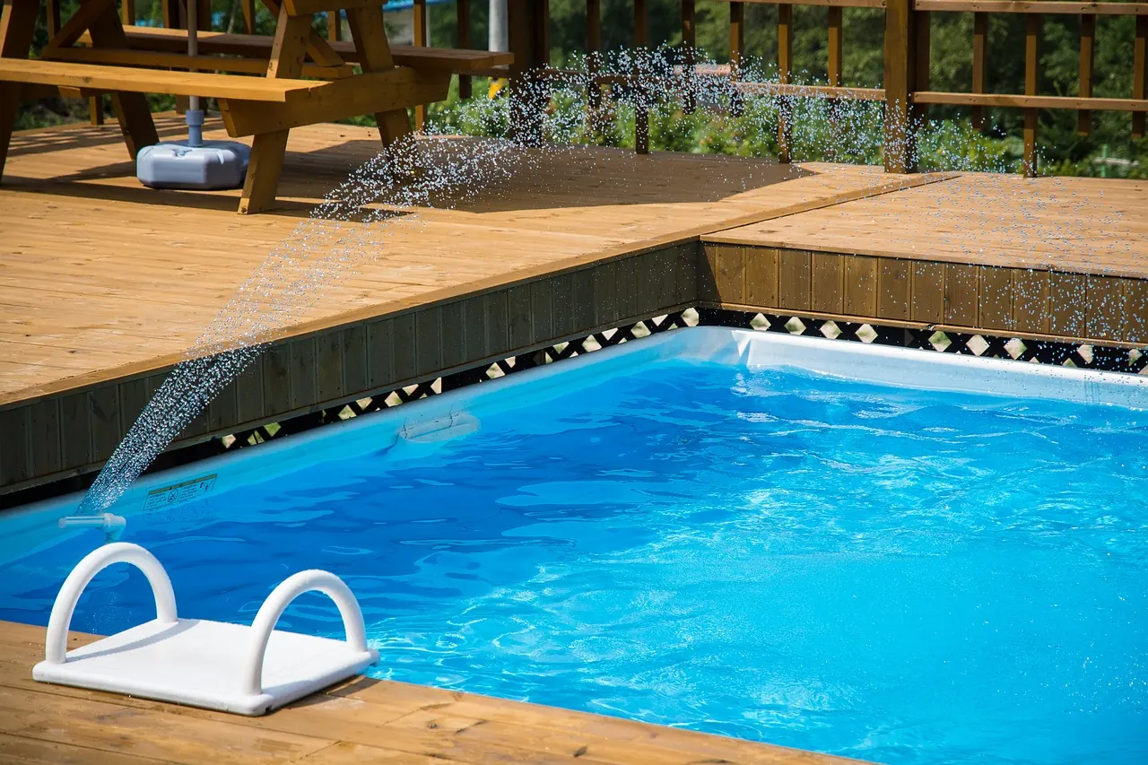 Piscine creusée entourée d'un patio de bois, prête pour le branchement de la pompe et du chauffe-eau